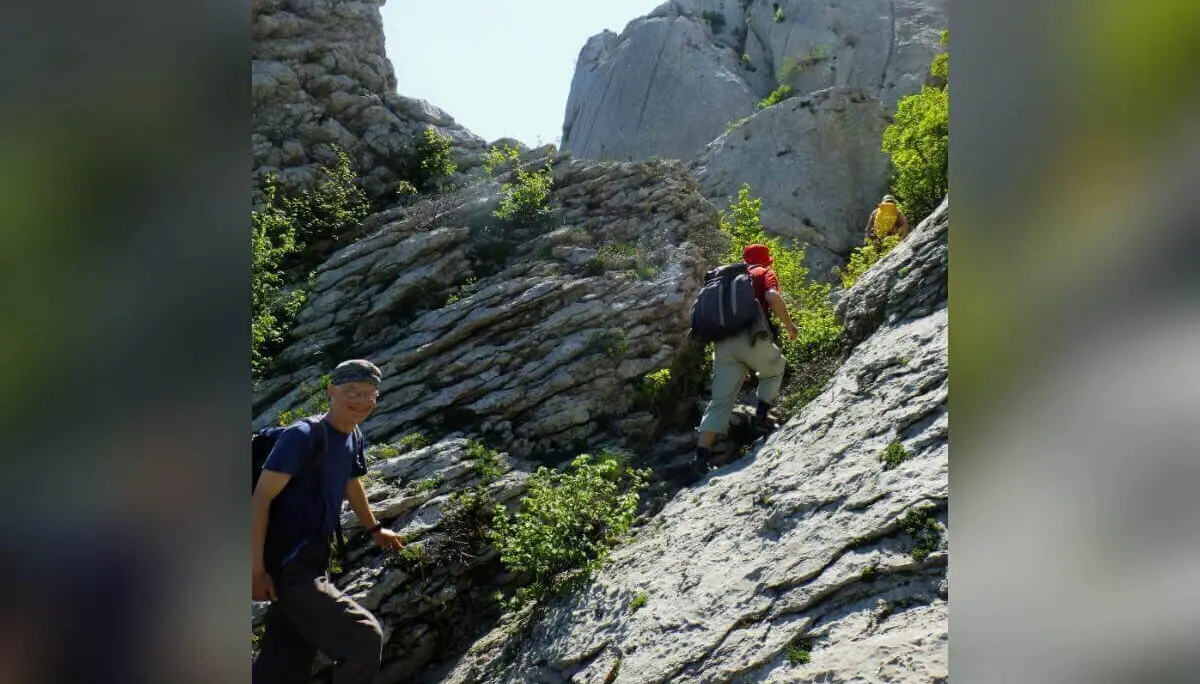 Drei Wandernde mit Rucksäcken steigen einen steinigen Bergpfad hinauf; steile Felswände im Hintergrund. | © DAV Markt Schwaben | Foto Hildegard Petschik