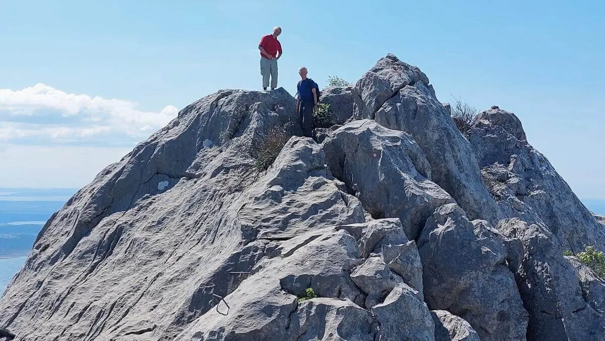 Zwei Personen stehen auf einem felsigen Gipfel mit Blick auf Meer und Inseln; klare Sicht und blauer Himmel. | © DAV Markt Schwaben | Foto Lutz Gründel