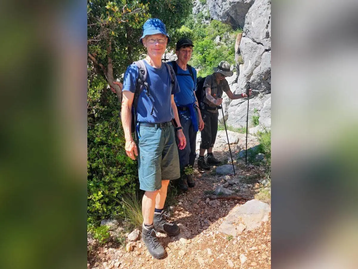 Drei Personen wandern durch felsiges Gelände; eine trägt blauen Hut, andere sind weiter hinten sichtbar. | © DAV Markt Schwaben | Foto Lutz Gründel