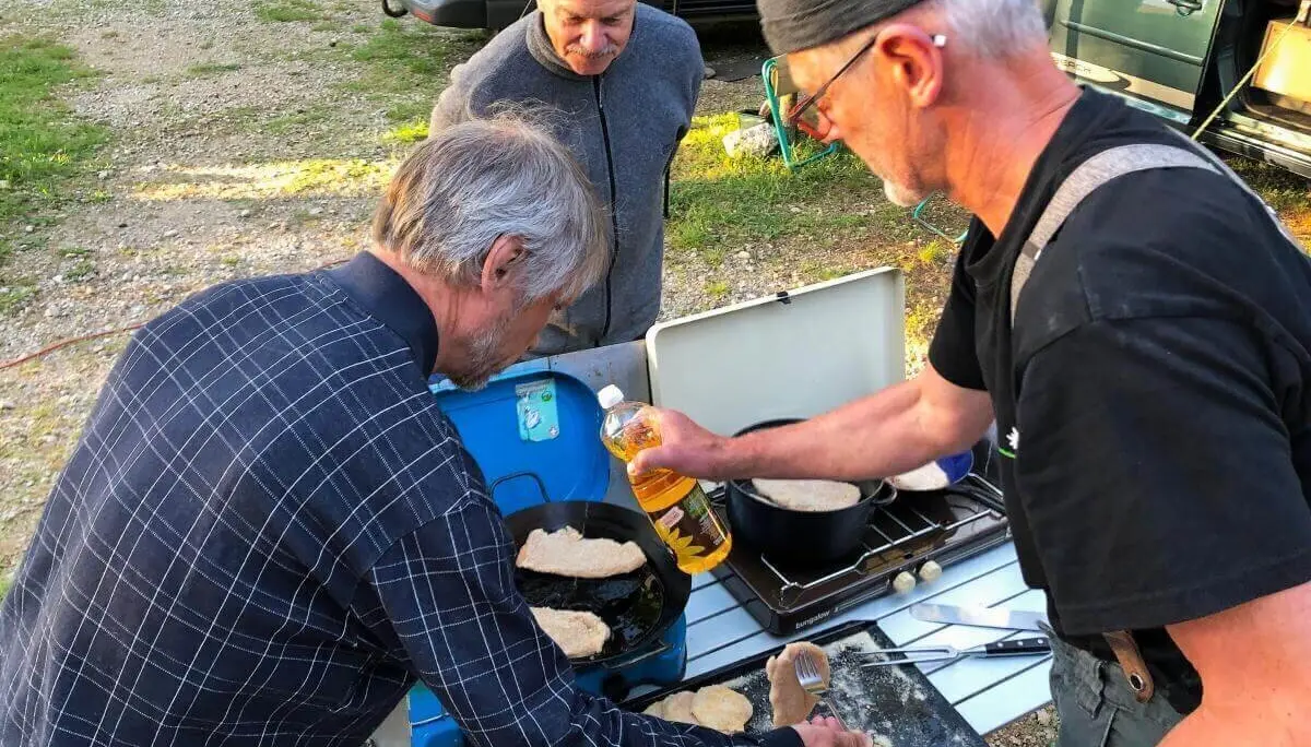 Drei Personen backen Fladenbrot am Zweiflammenkocher; Teig, Öl und Campingutensilien auf dem Tisch. | © DAV Markt Schwaben | Foto Hildegard Petschik