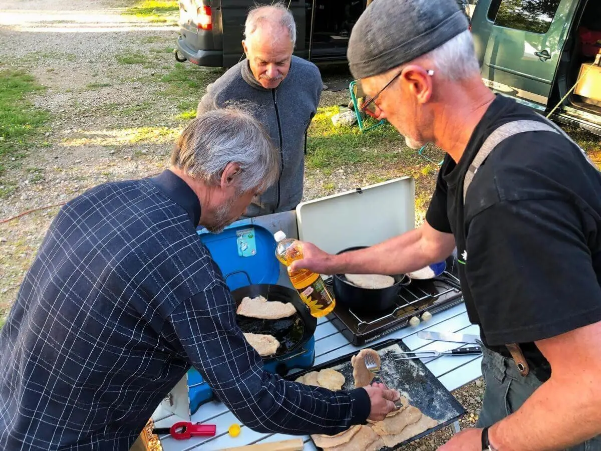 Drei Personen backen Fladenbrot am Zweiflammenkocher; Teig, Öl und Campingutensilien auf dem Tisch. | © DAV Markt Schwaben | Foto Hildegard Petschik