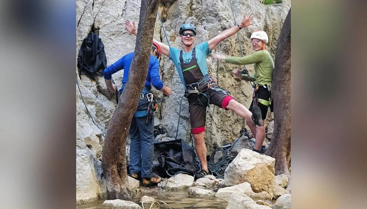 Drei Personen mit Kletterausrüstung posieren und lachen zwischen Felsen und flachem Wasserlauf. | © DAV Markt Schwaben | Foto Karin und Peter Tkaczuk