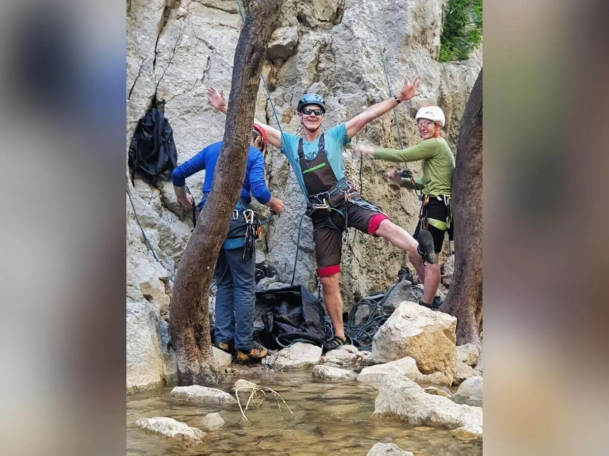 Drei Personen mit Kletterausrüstung posieren und lachen zwischen Felsen und flachem Wasserlauf. | © DAV Markt Schwaben | Foto Karin und Peter Tkaczuk