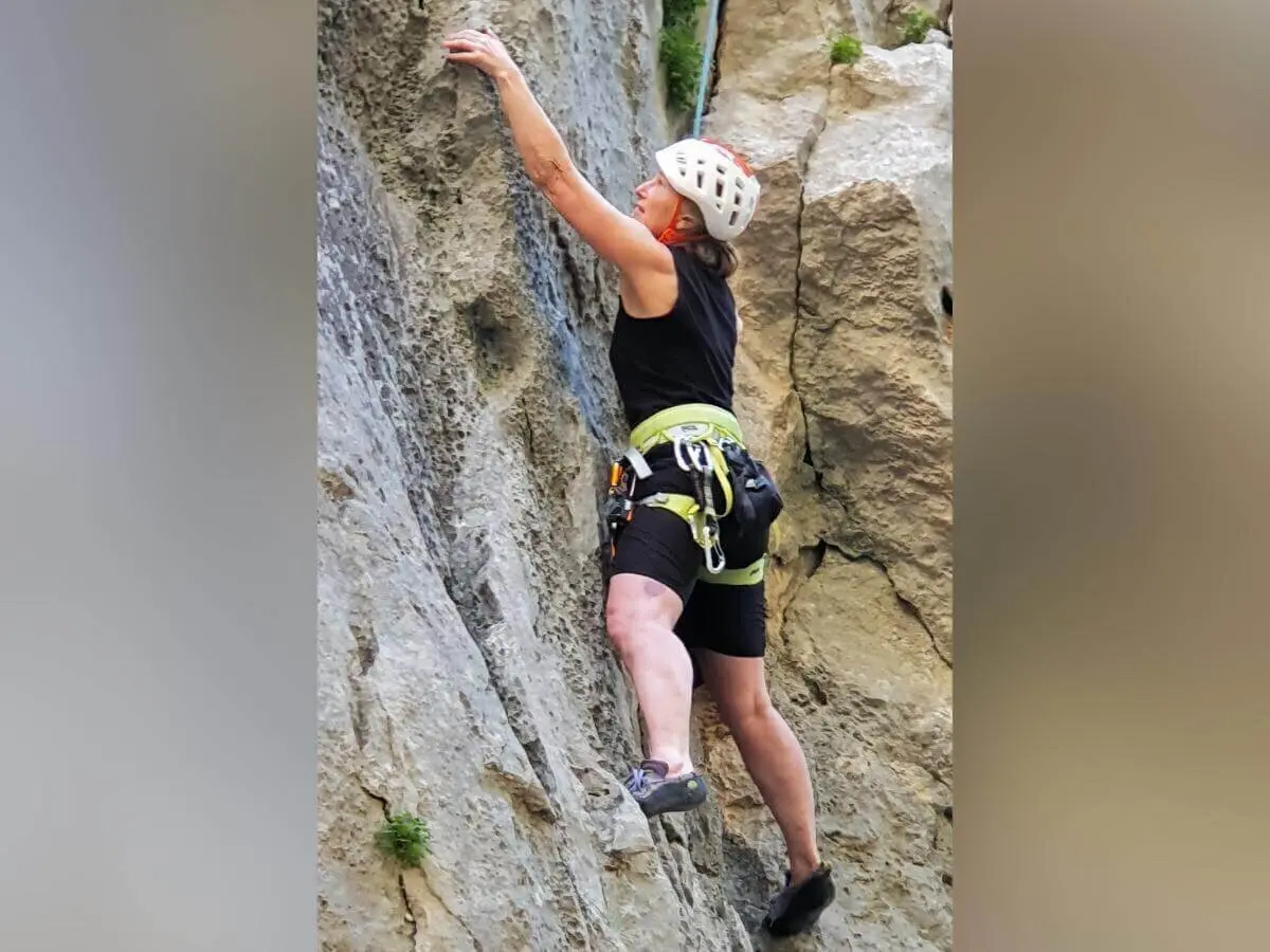 Eine Person mit Helm und Klettergurt steigt konzentriert an rauer Felswand mit kleinen Pflanzen empor. | © DAV Markt Schwaben | Foto Karin und Peter Tkaczuk