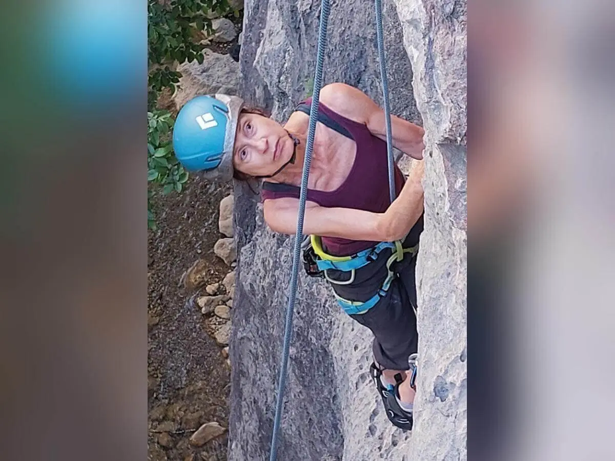 Eine Person mit blauem Helm klettert gesichert am Fels und schaut nach oben; Vegetation im Hintergrund. | © DAV Markt Schwaben | Foto Lutz Gründel
