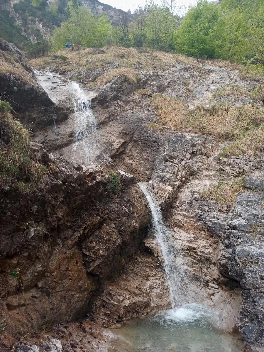 Ein friedliches Bild eines Wasserfalls, der inmitten der bewaldeten Umgebung über die Felsen hinabstürzt. | © DAV Markt Schwaben | Foto Tanja Döhler