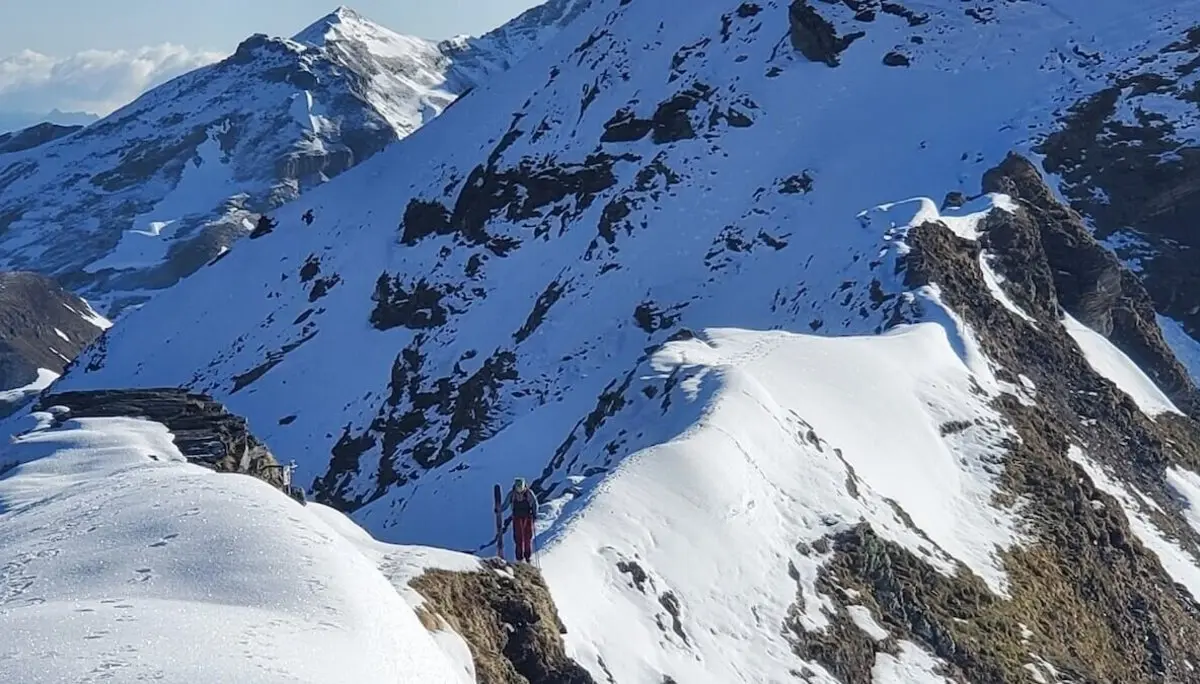 Am Grat zum Niedersachsenhaus Alt-Text: Ein Bergsteiger mit Ski am Rucksack folgt einem schmalen, verschneiten Gratweg in hochalpinem Gelände | © DAV Markt Schwaben | Foto: Walter Kressirer