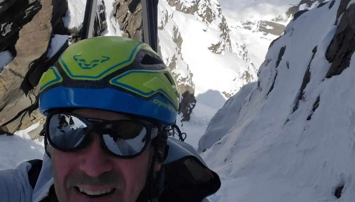 Ein Bergsteiger macht ein Selfie in einer steilen, verschneiten Ausstiegsrinne mit schroffen Felsen – Skihelm und Ausrüstung sichtbar, hochalpines Gelände. | © DAV Markt Schwaben | Foto: Walter Kressirer
