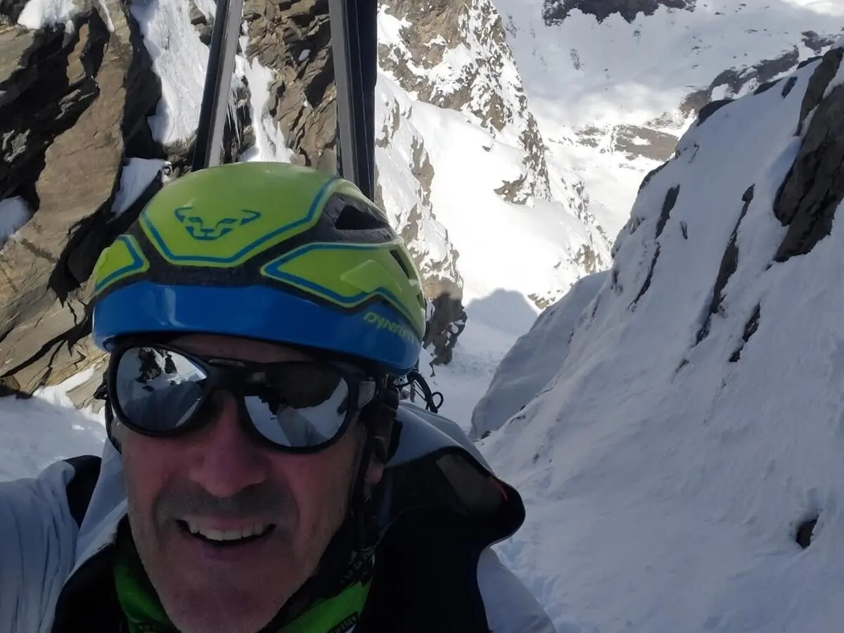 Ein Bergsteiger macht ein Selfie in einer steilen, verschneiten Ausstiegsrinne mit schroffen Felsen – Skihelm und Ausrüstung sichtbar, hochalpines Gelände. | © DAV Markt Schwaben | Foto: Walter Kressirer