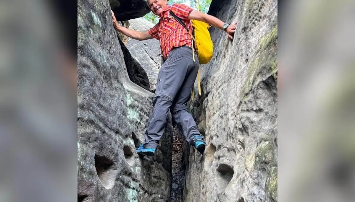 Wandernde Person mit gelbem Rucksack nutzt Trittkerben in schmaler Felsspalte, umgeben von rauer Steinstruktur. | © DAV Markt Schwaben | Foto Edith Zerrle