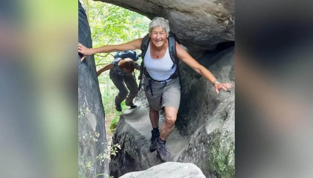 Zwei Personen passieren enge Felslücke, vorne lächelnd, hinten gebückt, umgeben von Grün und Felsformationen. | © DAV Markt Schwaben | Foto Michaela Haaß