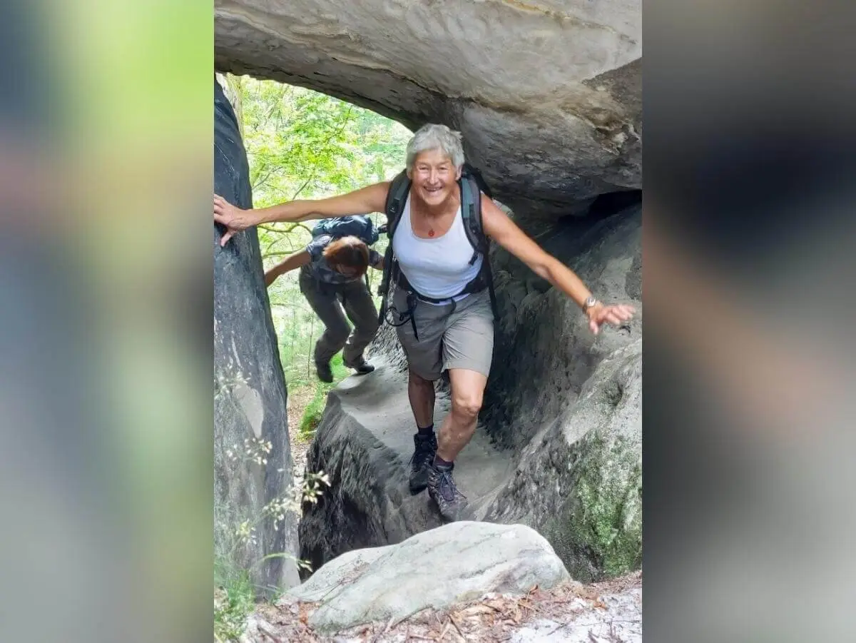 Zwei Personen passieren enge Felslücke, vorne lächelnd, hinten gebückt, umgeben von Grün und Felsformationen. | © DAV Markt Schwaben | Foto Michaela Haaß