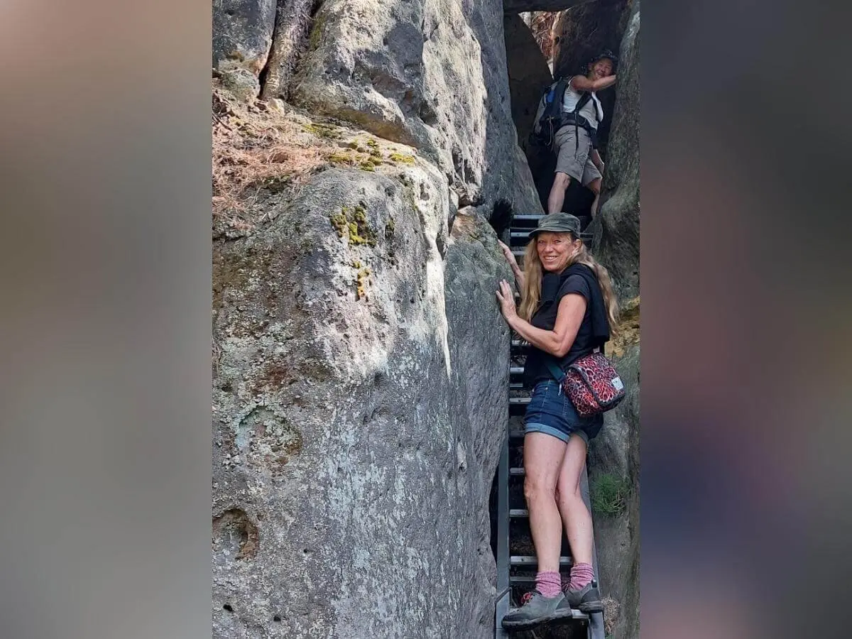 Zwei Personen steigen schmale Metallleiter zwischen Felsen hinauf, umgeben von Moos und rauer Steinstruktur. | © DAV Markt Schwaben | Foto Lutz Gründel