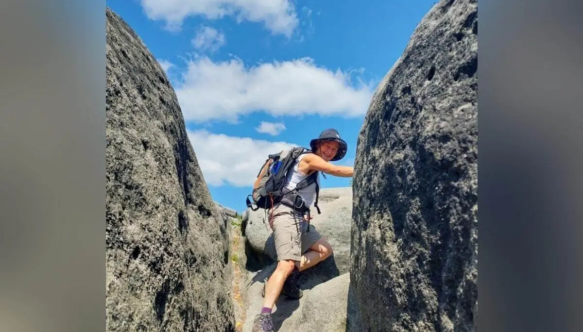Person mit Sonnenhut und Rucksack klettert zwischen zwei Felsen, blauer Himmel im Hintergrund. | © DAV Markt Schwaben | Foto Angelika Göthe-Volkert