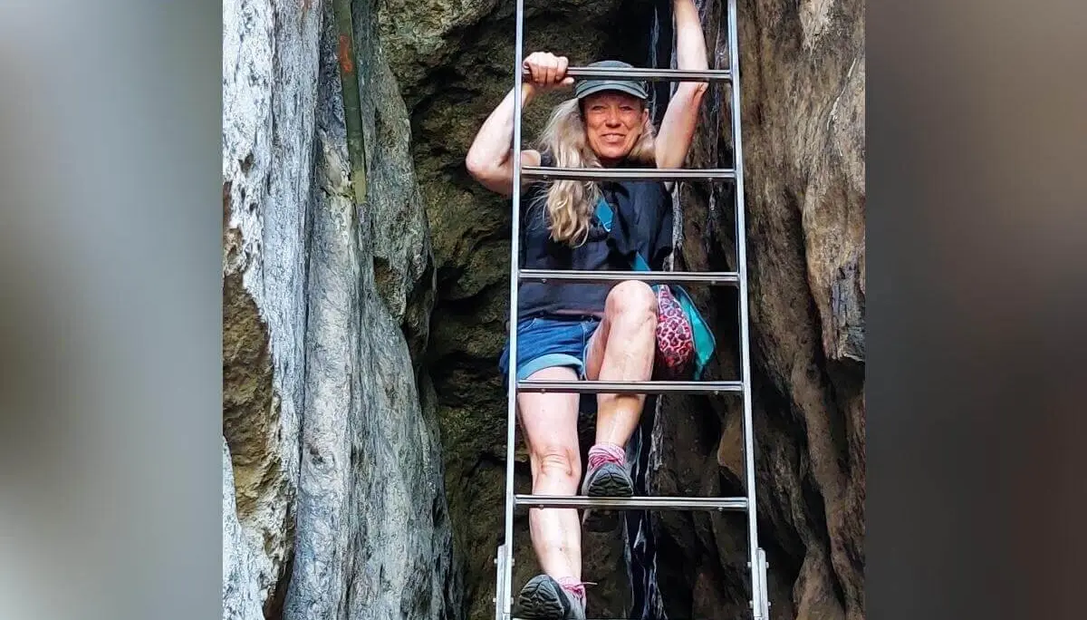 Person mit bunter Tasche steigt senkrechte Leiter zwischen Felswänden, umgeben von rauer Struktur. | © DAV Markt Schwaben | Foto Lutz Gründel