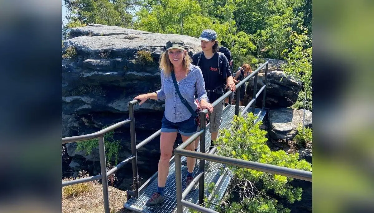 Zwei Personen überqueren Metallbrücke, links Felswand, rechts dichter Wald, sonniger Tag. | © DAV Markt Schwaben | Foto Yvonne Haaß