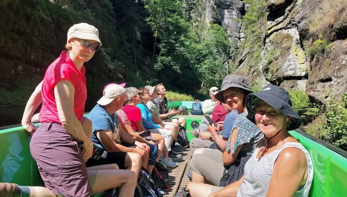 Gruppe sitzt im grünen Boot zwischen steilen Felswänden, umgeben von Wald, Licht fällt durch die Bäume. | © DAV Markt Schwaben | Foto Lutz Gründel