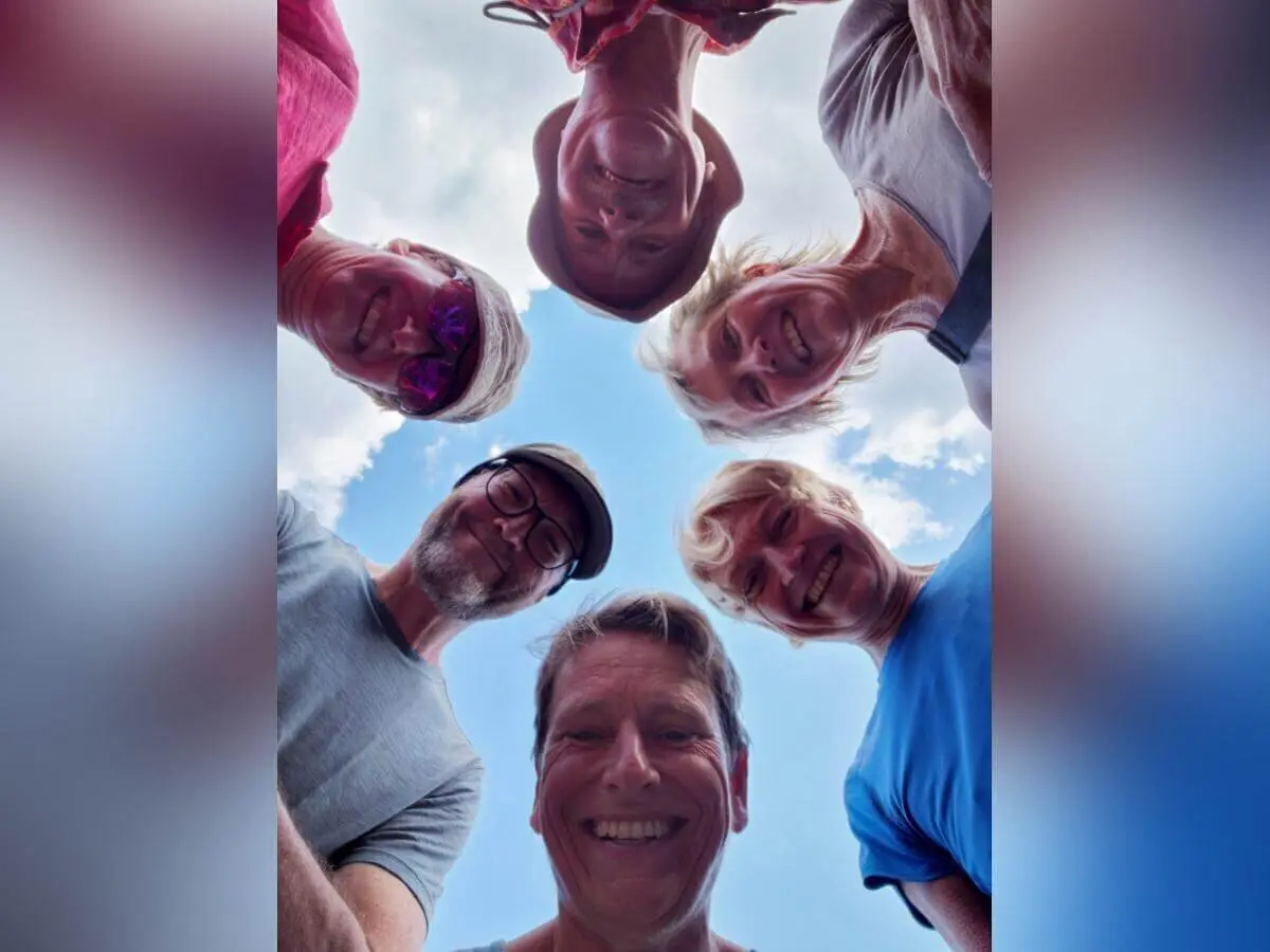 Sechs Personen stehen im Kreis und blicken lachend in die Kamera; über ihnen blauer Himmel mit leichten Wolken. | © DAV Markt Schwaben | Foto Sabine Hainz