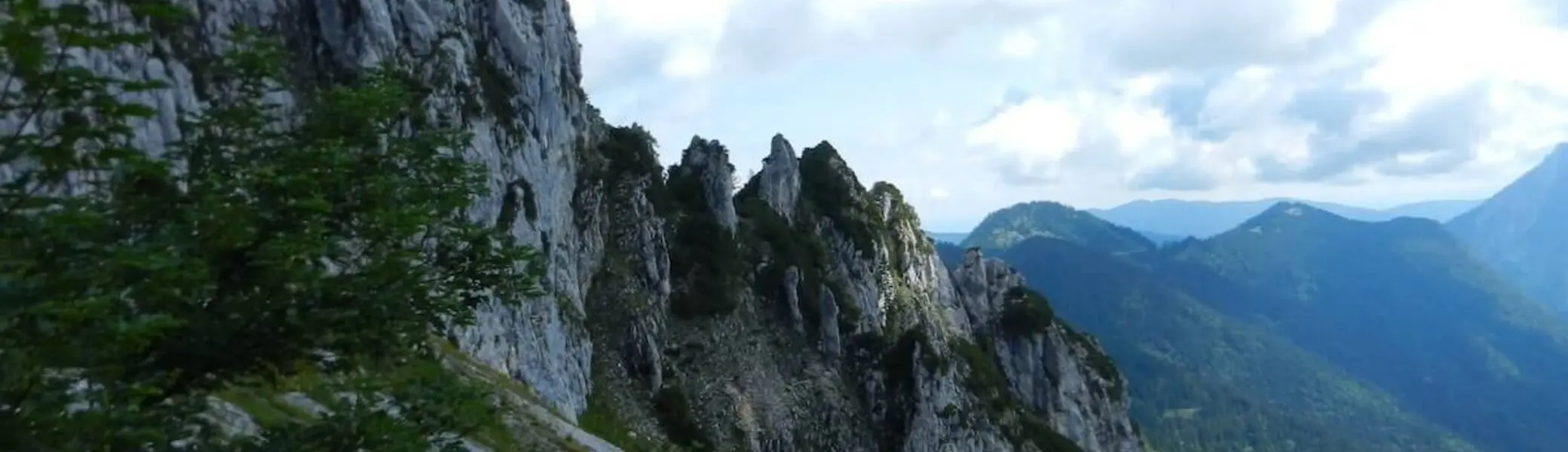Steile Felsformation der Hördlwand vor grüner Tallandschaft – im Fokus steht die eindrucksvolle Naturkulisse. | © DAV Markt Schwaben