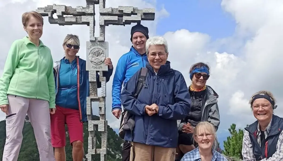 Sieben Erwachsene posieren am Gipfelkreuz der Hördlwand. | © DAV Markt Schwaben