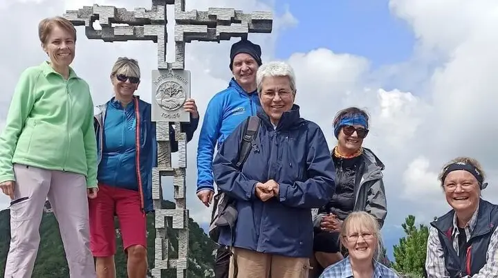 Sieben Erwachsene posieren am Gipfelkreuz der Hördlwand. | © DAV Markt Schwaben