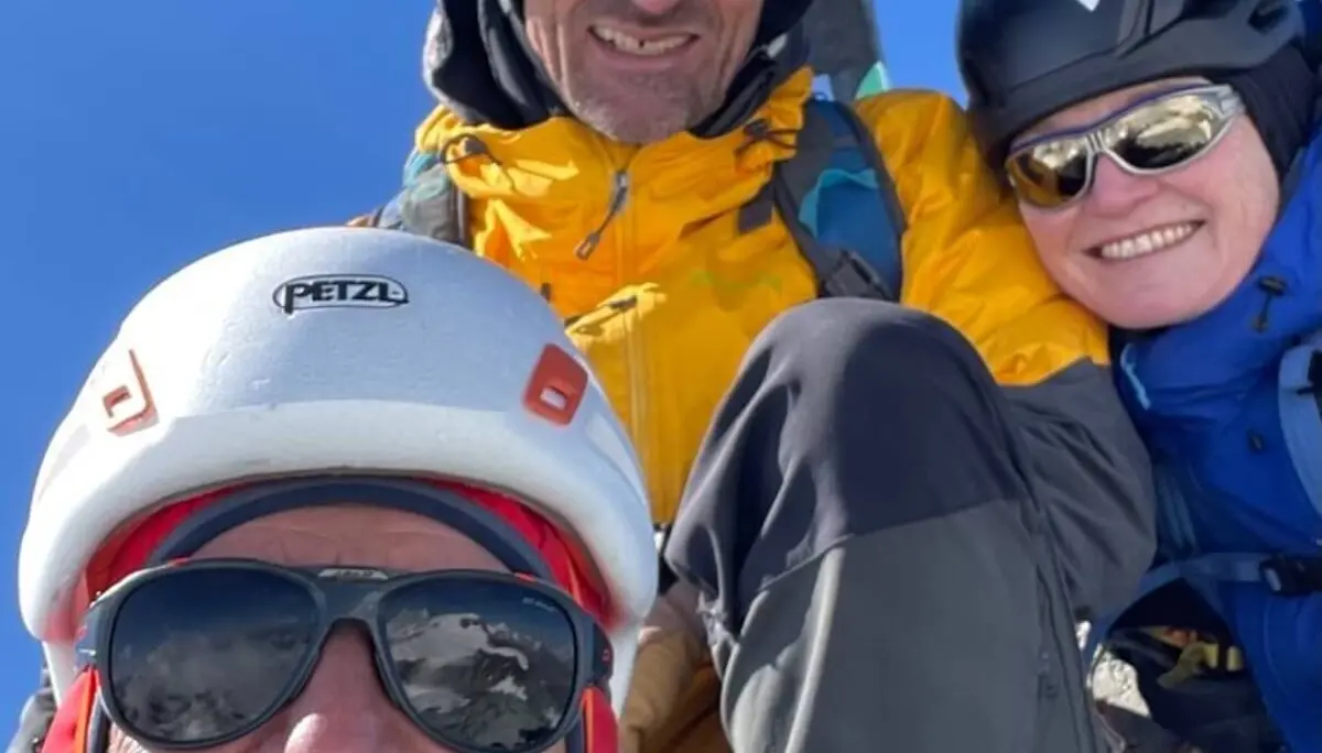 Drei Bergsteiger stehen vor einem Gipfelkreuz in den Westalpen – blauer Himmel und Kletterausrüstung unterstreichen das Ziel erreicht. | © DAV Markt Schwaben | Christian Reischl