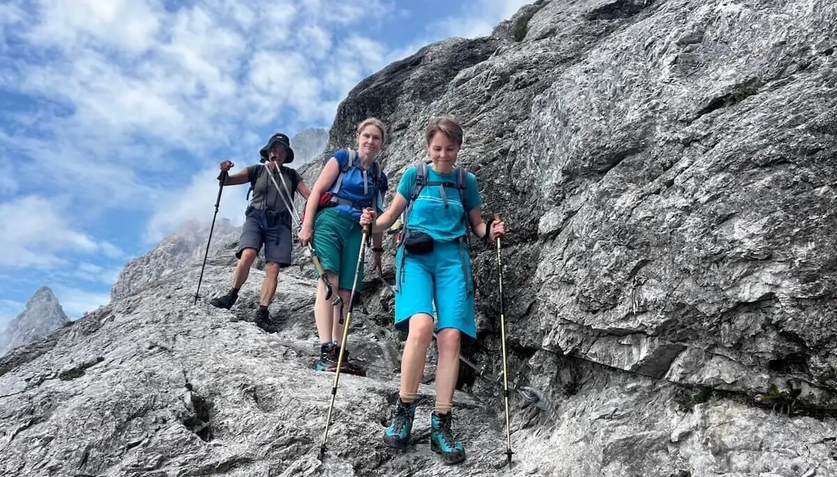 Drei Wandernde steigen auf felsigem Pfad vom Steiglpass ab – mit Trekkingausrüstung vor klarer Bergkulisse und blauem Himmel. | © DAV Markt Schwaben | Foto: Markus Sellmeier