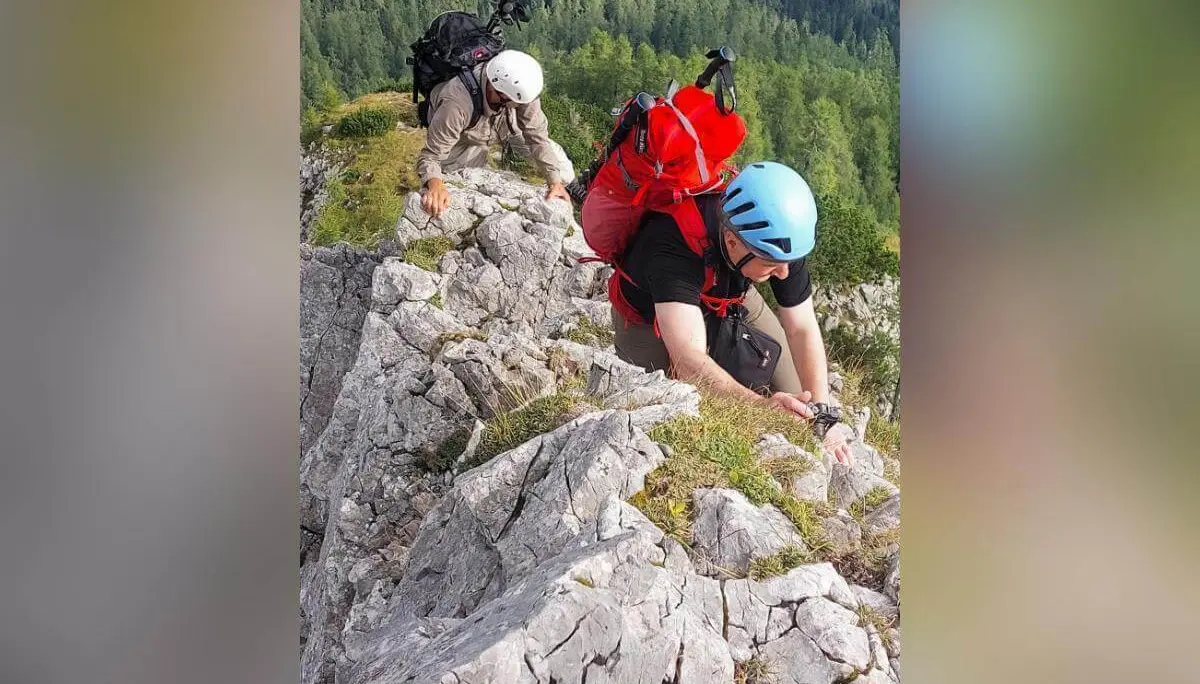 Zwei Bergsteiger sichern sich auf steiler Felskante, im Hintergrund Waldhang und felsige Bergflanke. | © DAV Markt Schwaben · Foto: Lutz Gründel