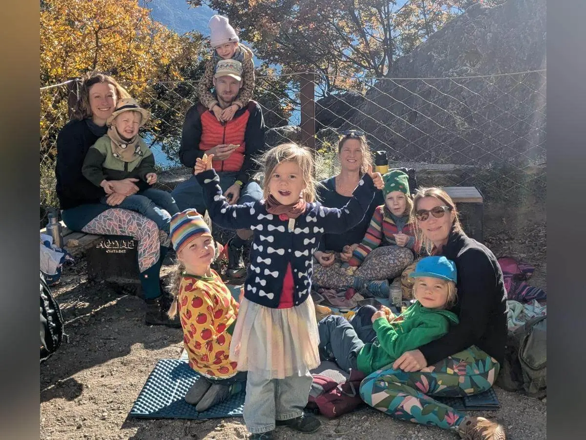 Fünf Kinder sitzen auf einer roten Bank vor einer hellen Wand und essen Eis. Ein Kind hält zusätzlich eine Puppe. Alle tragen bunte Kleidung. | © DAV Markt Schwaben · Foto: Silke Titze