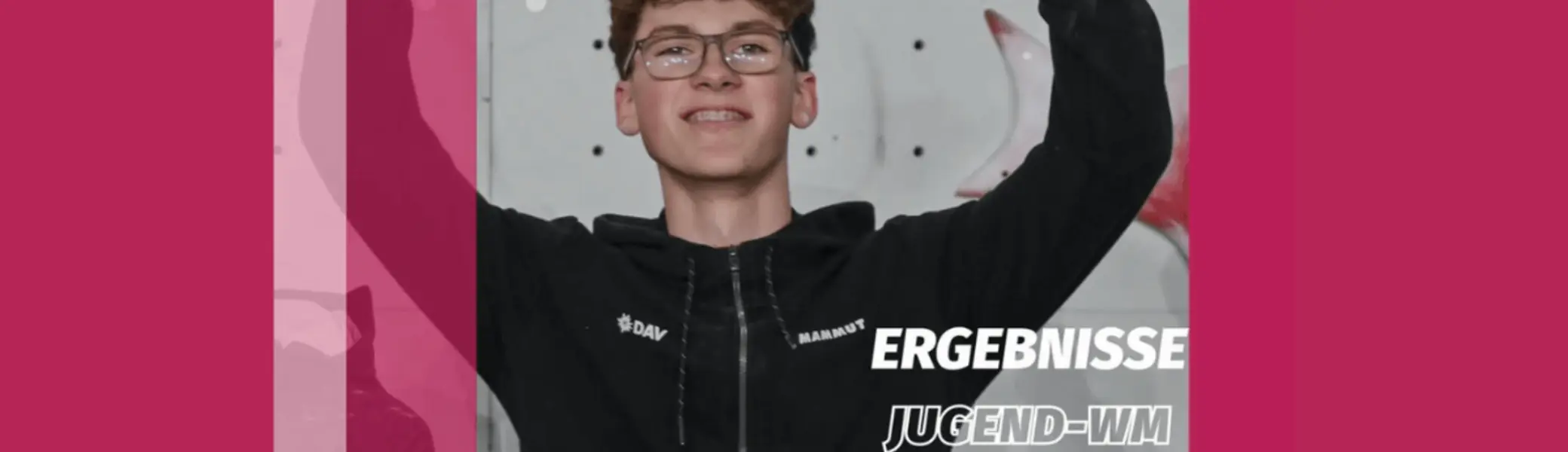 Aodhán Umlauf steht stolz vor einer Kletterwand, die Arme siegreich erhoben. Er trägt eine schwarze Sportjacke mit den Logos von DAV und Mammut. Im Bild ist der Text ‚1. Platz Jugend-WM‘ zu sehen. Das Foto feiert seinen Sieg bei der Jugend-Weltmeisterschaft im Sportklettern. | © iFSC Instagram: @ifsclimbing