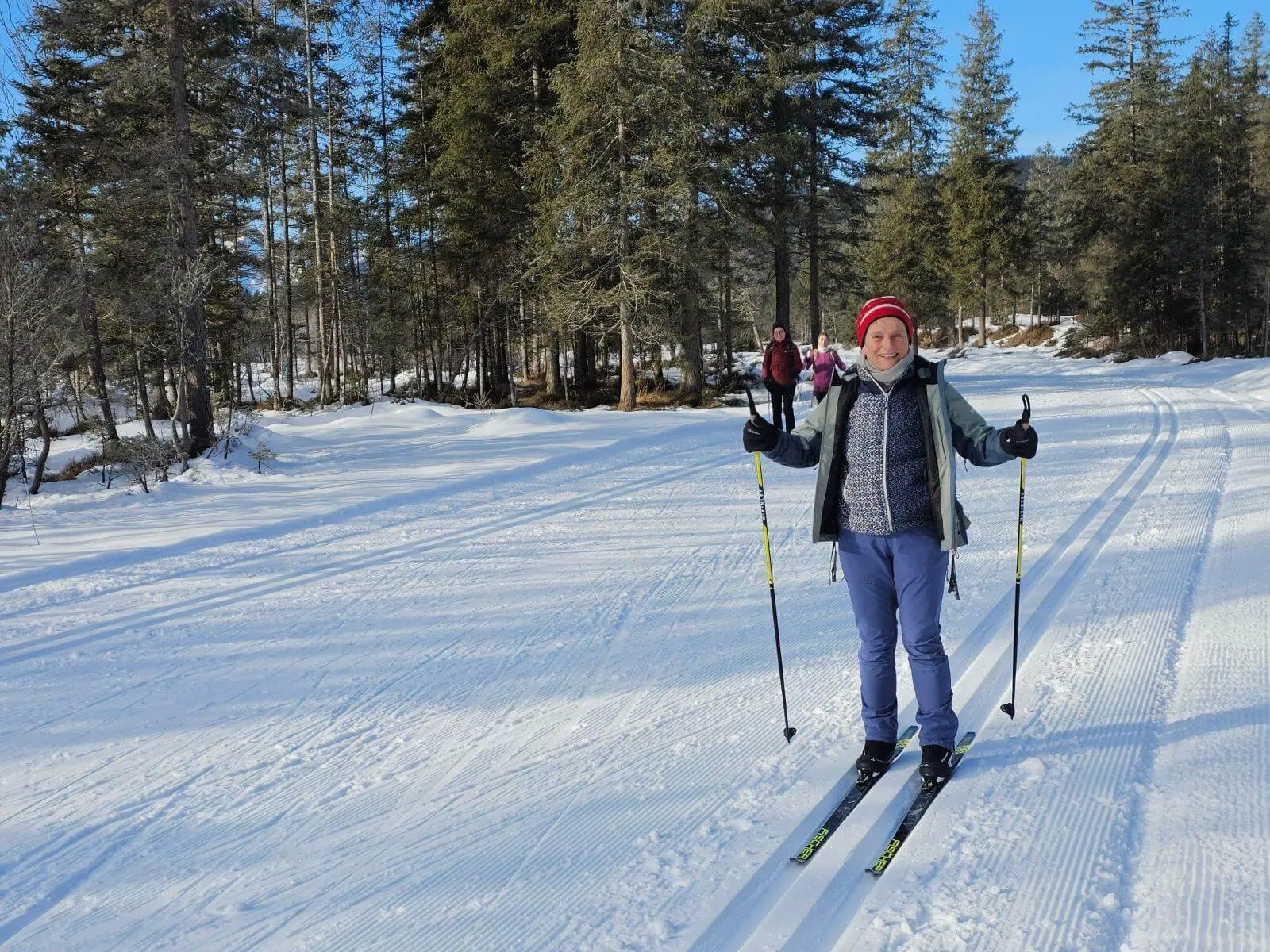 Eine Person läuft auf frisch gespurter Loipe durch verschneiten Wald. Weitere Teilnehmende folgen auf der Kanada-Loipe im Isartal. | © DAV Markt Schwaben/Lutz Gründel