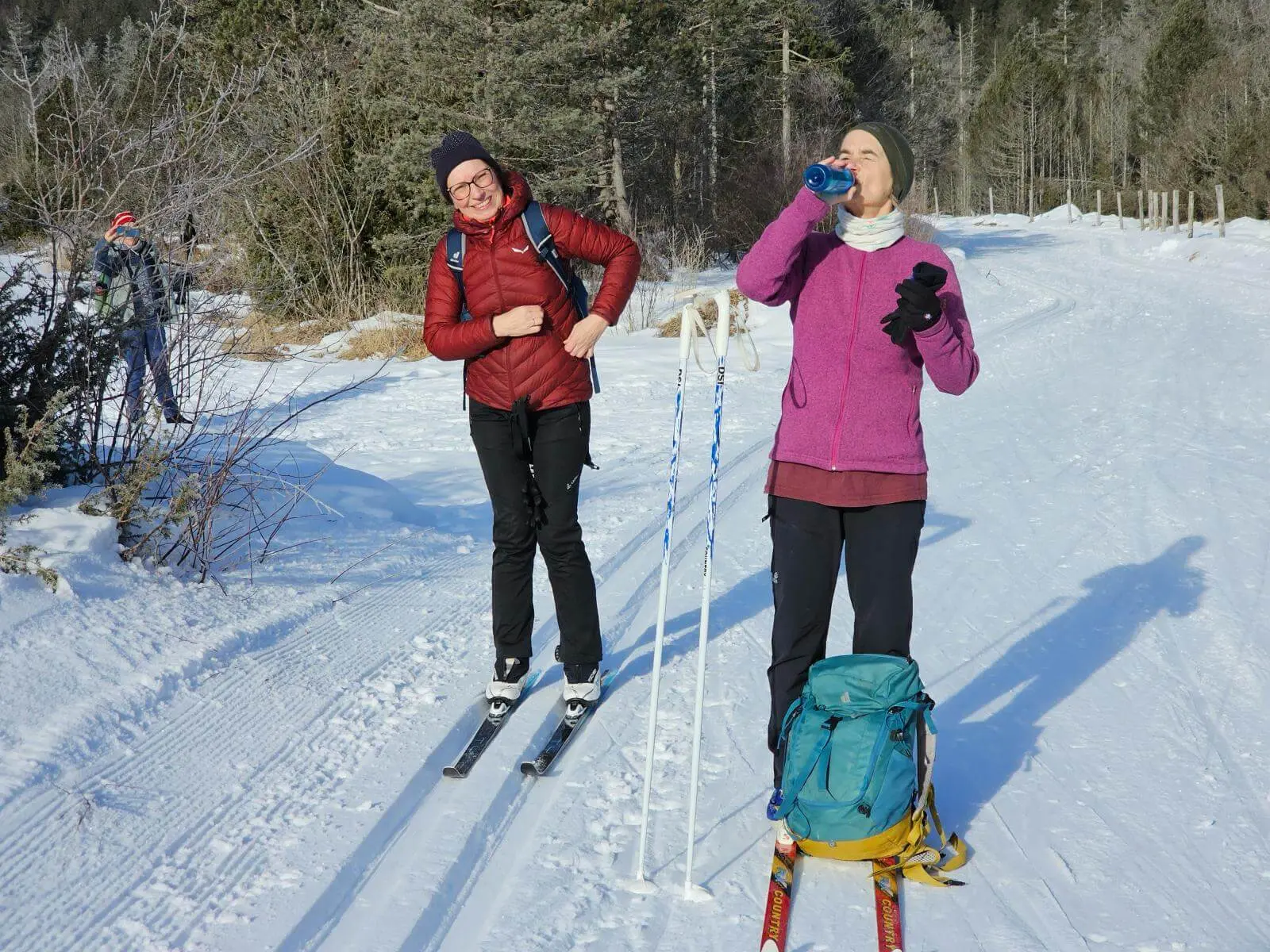 Zwei Langläufer machen auf der verschneiten Kanadaloipe eine Pause. Im Hintergrund verläuft die gespurte Strecke durch die Winterlandschaft. | © DAV Markt Schwaben/Lutz Gründel