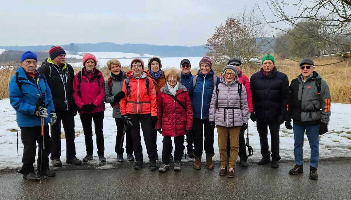 Vierzehn Seniorinnen und Senioren stehen auf einem winterlichen Weg beisammen; im Hintergrund liegen verschneite Felder und Bäume. | © DAV Markt Schwaben/Hubert Inhofer