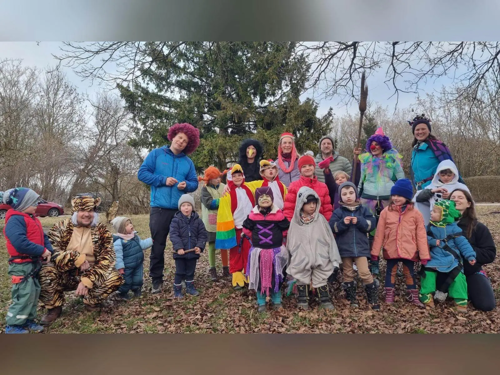 Eine große Gruppe verkleideter Kinder und Erwachsener steht gemeinsam auf einer Wiese, bunt kostümiert vor Bäumen beim Faschingsklettern. | © DAV Markt Schwaben