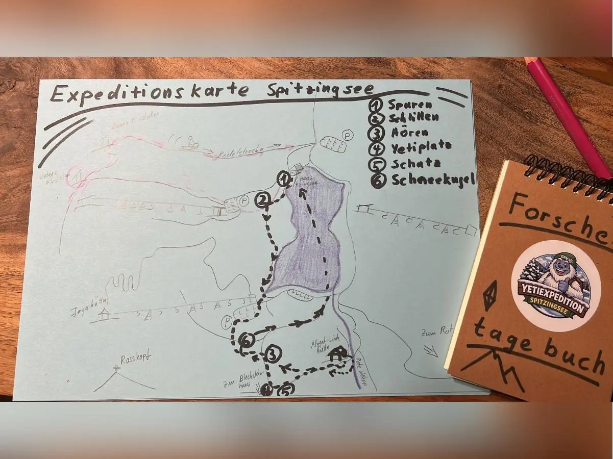 Handgezeichnete Expeditionskarte mit nummerierten Stationen rund um den Spitzingsee; daneben ein braunes Forscher‑Tagebuch mit Yeti‑Sticker. | © DAV Markt Schwaben, Familiengruppe