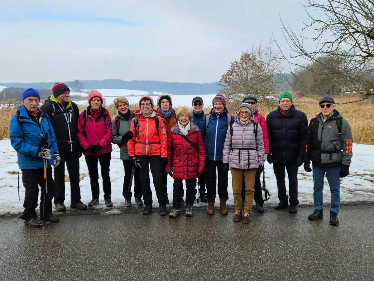 Vierzehn Seniorinnen und Senioren stehen auf einem winterlichen Weg beisammen; im Hintergrund liegen verschneite Felder und Bäume. | © DAV Markt Schwaben | Foto: Hubert Inhofer