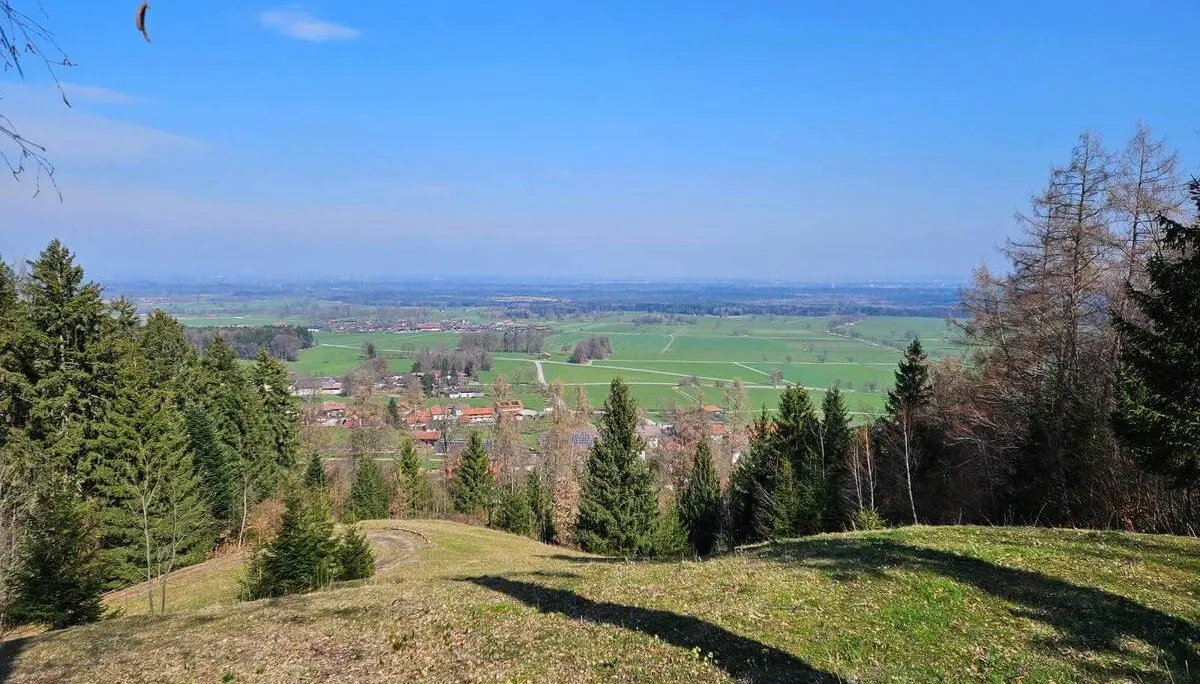 Weiter Blick von einer Anhöhe über Wiesen, Wälder und Ortschaften bei Bad Feilnbach unter blauem Himmel während der Seniorenwanderung. | © DAV Markt Schwaben