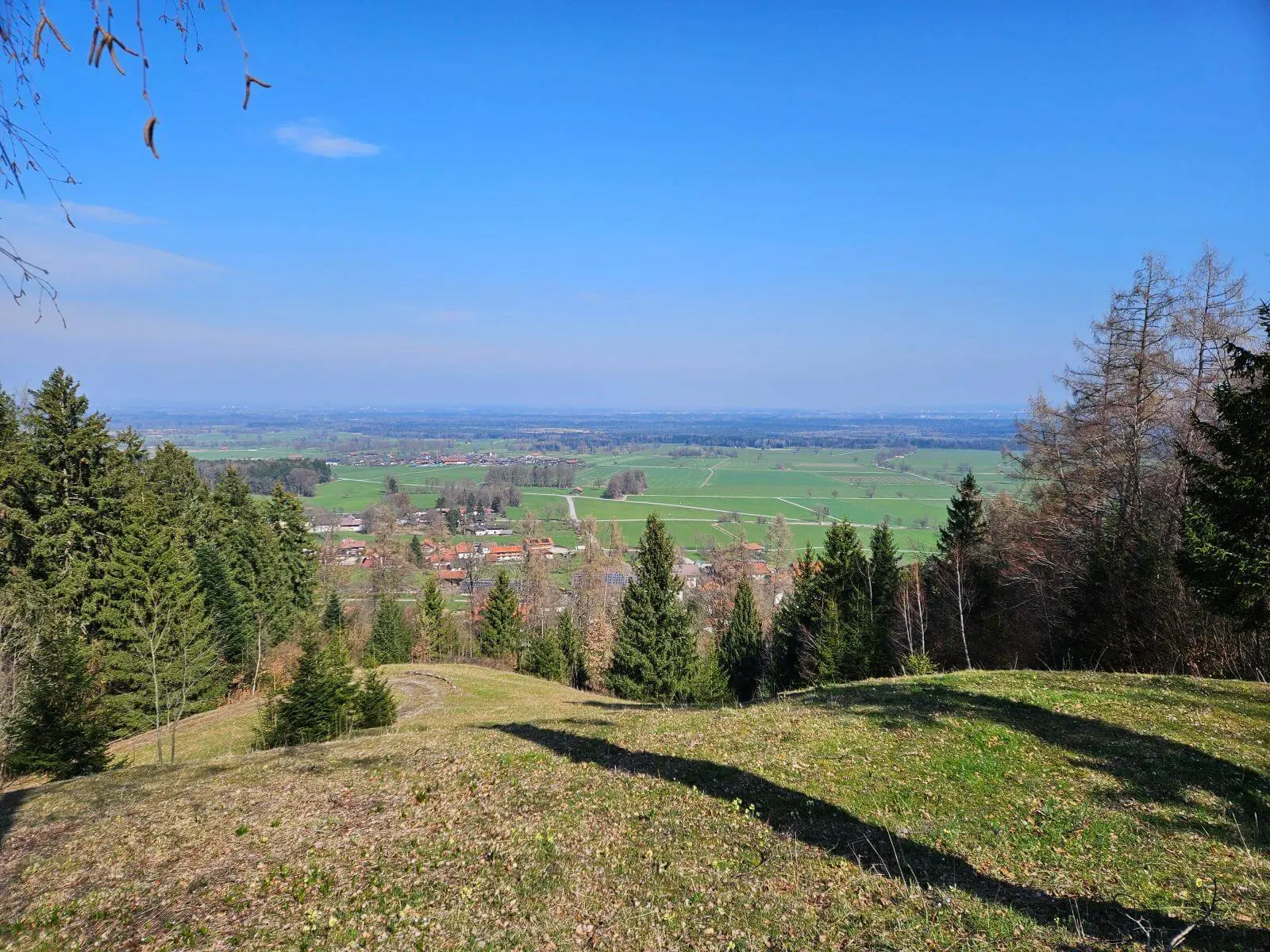 Weiter Blick von einer Anhöhe über Wiesen, Wälder und Ortschaften bei Bad Feilnbach unter blauem Himmel während der Seniorenwanderung. | © DAV Markt Schwaben