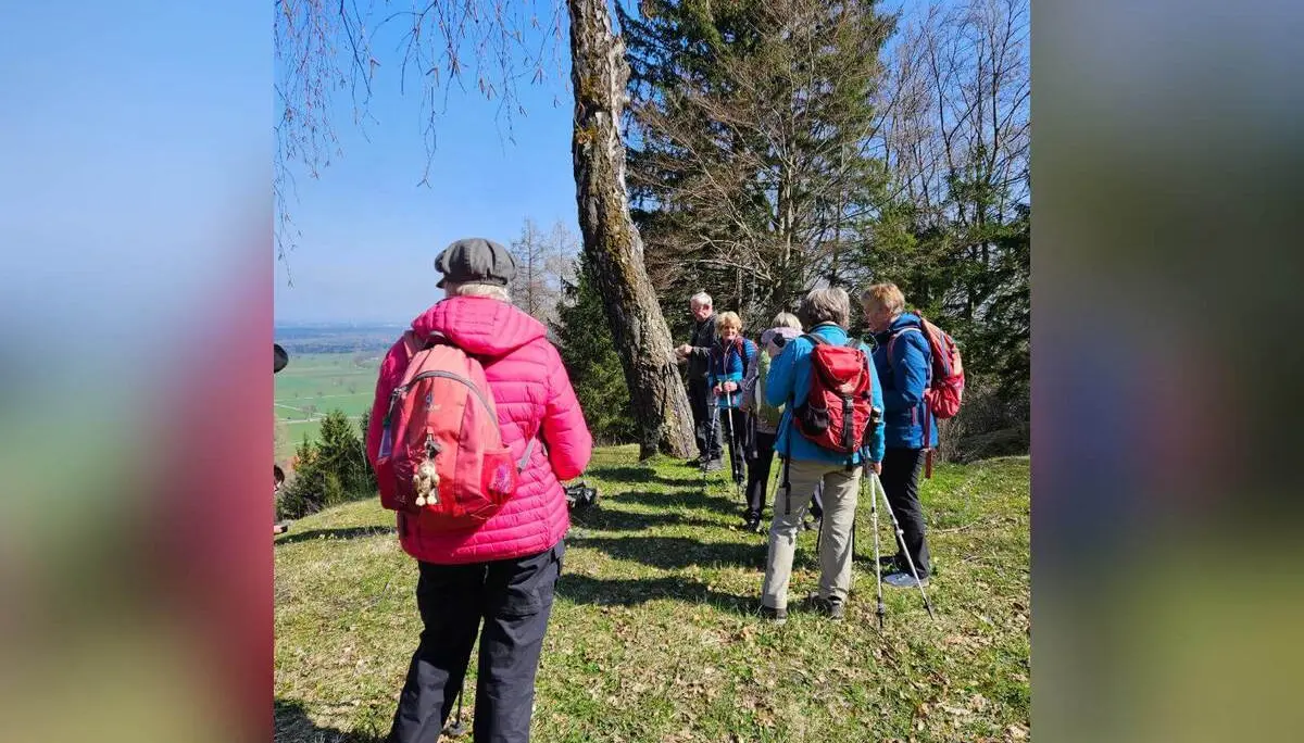 Teilnehmende der Seniorengruppe stehen auf einer sonnigen Wiese mit Wanderstöcken, im Hintergrund Blick ins Tal bei Bad Feilnbach. | © DAV Markt Schwaben