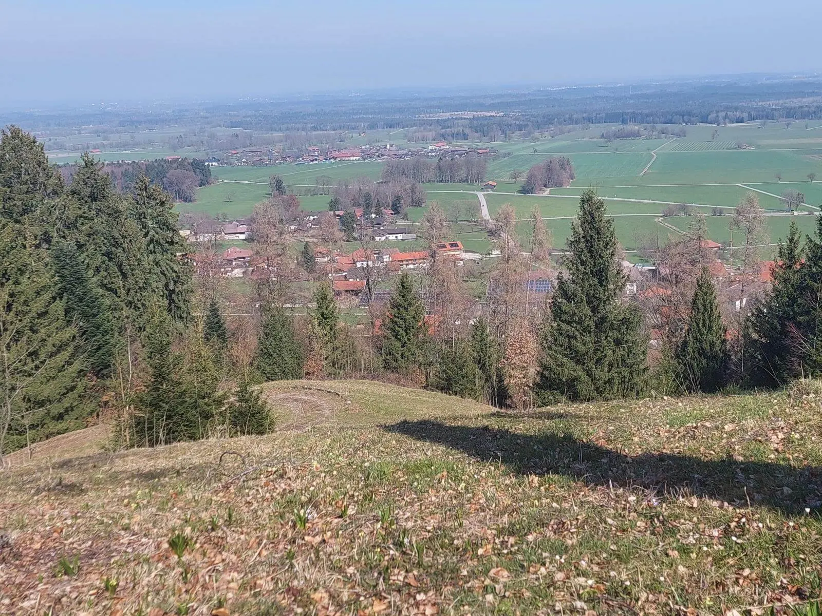 Blick von einer Anhöhe über einen Ort mit roten Dächern, umgeben von Wiesen und Wäldern im Voralpenland bei Bad Feilnbach. | © DAV Markt Schwaben