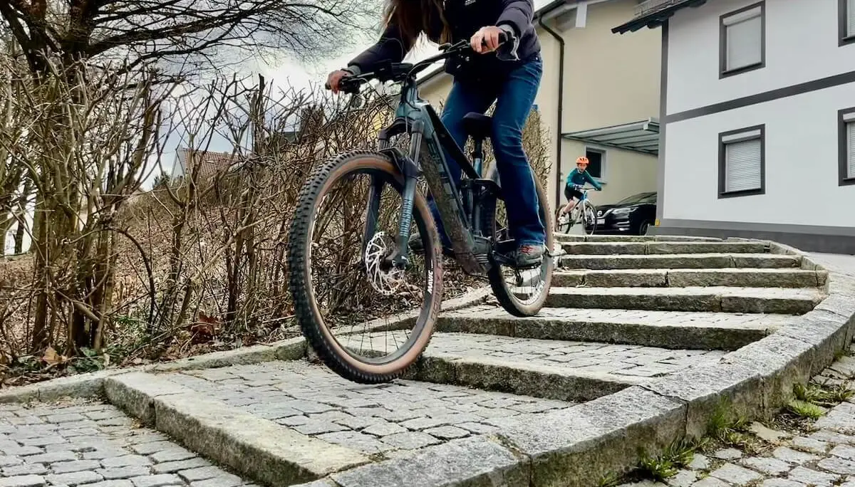 Zwei Radfahrende fahren kontrolliert eine steinerne Treppe hinab; im Vordergrund ein Mountainbike, dahinter ein weiterer Fahrer im Wohngebiet. | © DAV Markt Schwaben/Miron Thoms