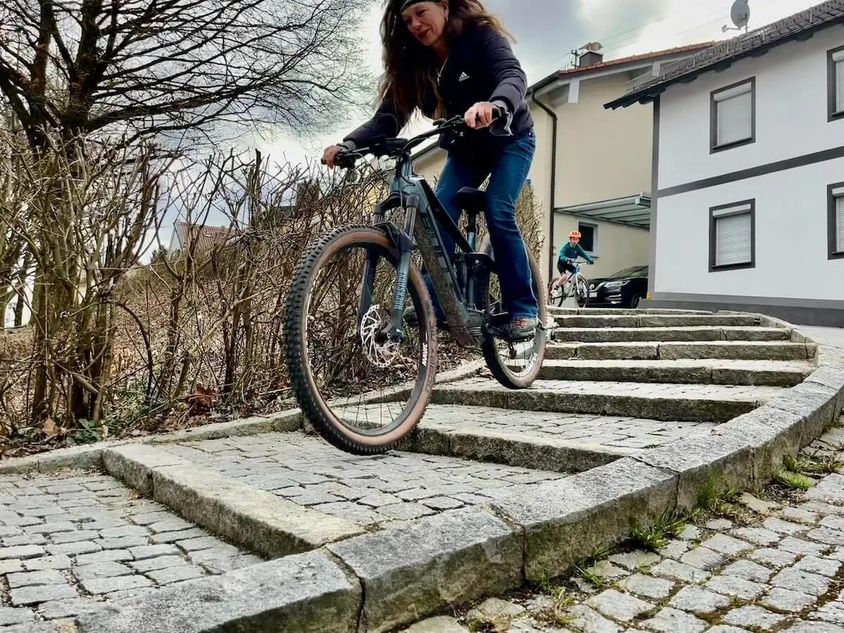 Zwei Radfahrende fahren kontrolliert eine steinerne Treppe hinab; im Vordergrund ein Mountainbike, dahinter ein weiterer Fahrer im Wohngebiet. | © DAV Markt Schwaben/Miron Thoms