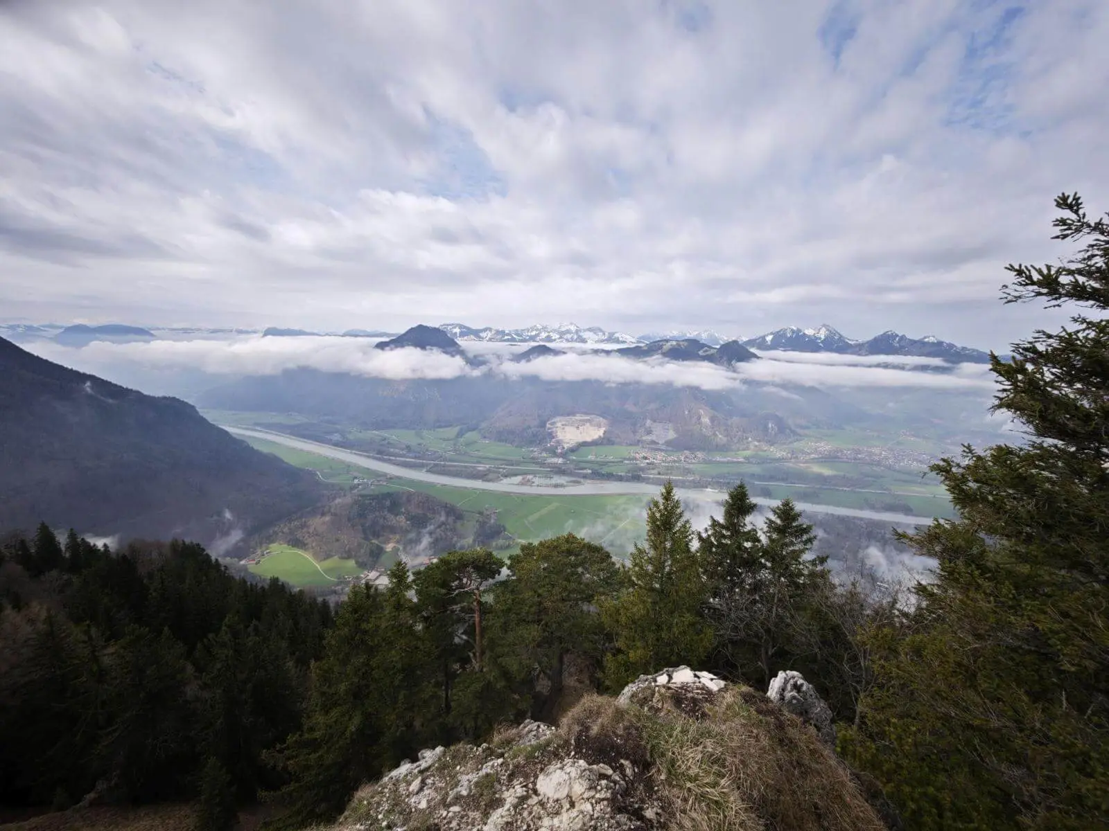 Weitblick vom felsigen Hang über bewaldete Hänge ins Inntal mit Flusslauf, darüber schweben Wolken vor alpiner Bergkulisse. | © DAV Markt Schwaben/Erwin Matzinger