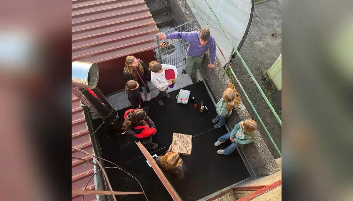 Jugendgruppe steht abends im Turmraum um Pizza und Getränke; Blick von oben zeigt Dach, Geländer und Umgebung. | © DAV Markt Schwaben/Wiebke Rauschenbach