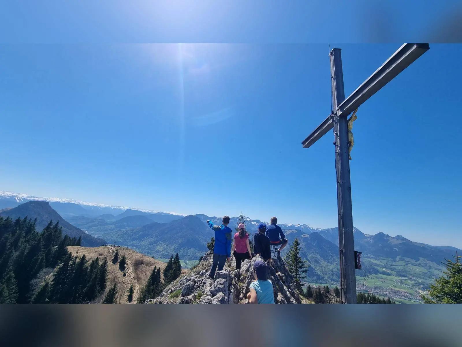 Familiengruppe steht am Gipfelkreuz des Heubergs und blickt über weites Bergpanorama mit Tälern und Gipfeln. | © DAV Markt Schwaben/Maria Wenisch