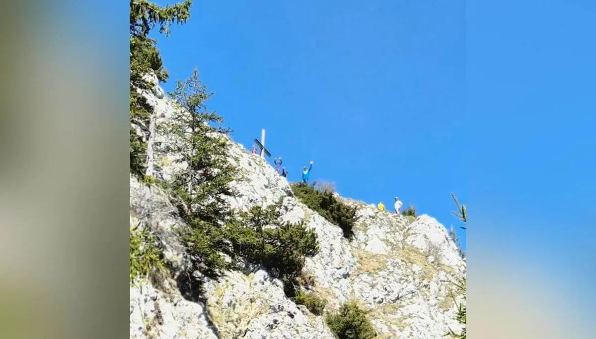 Mehrere Personen klettern auf steilem, felsigem Grat der Wasserwand; von unten aufgenommen, mit Gipfelkreuz und blauem Himmel. | © DAV Markt Schwaben/Anna Thoms