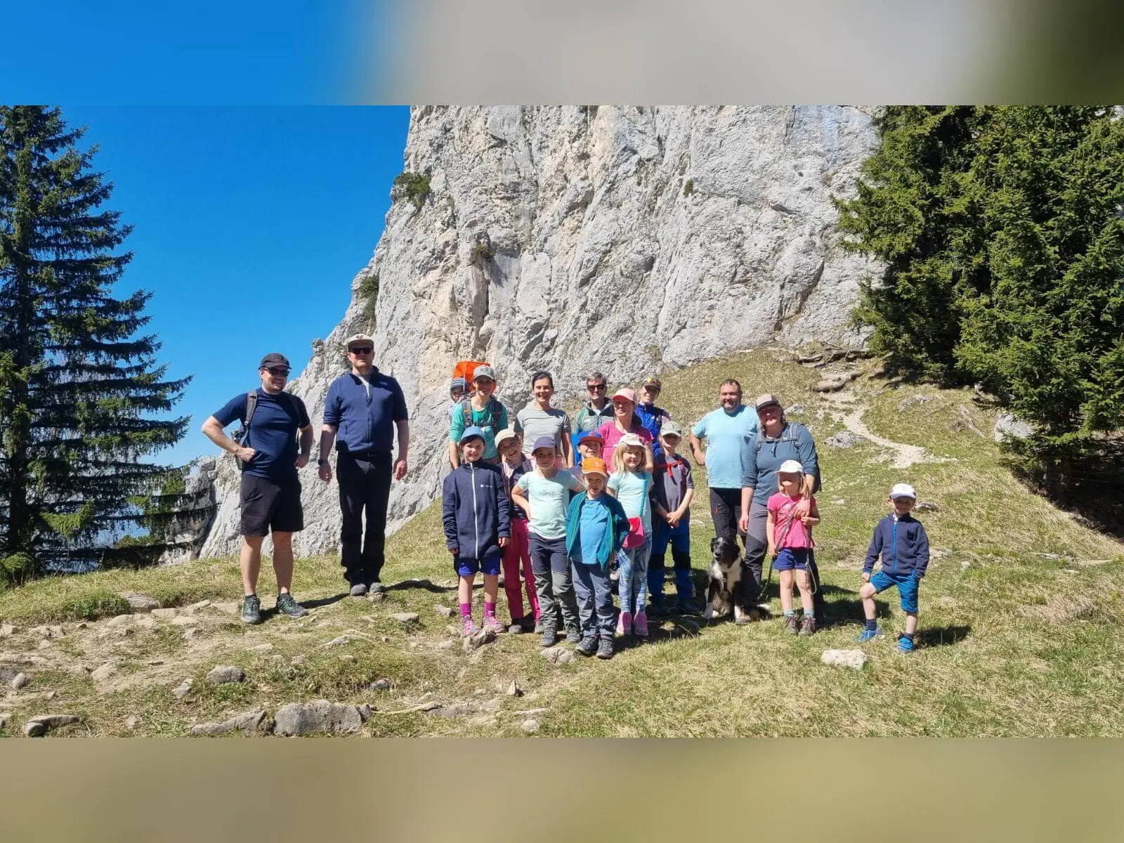 Familiengruppe mit Kindern steht auf einer Wiese vor steiler Felswand der Wasserwand; alle versammelt nach der Tour. | © DAV Markt Schwaben/Maria Wenisch