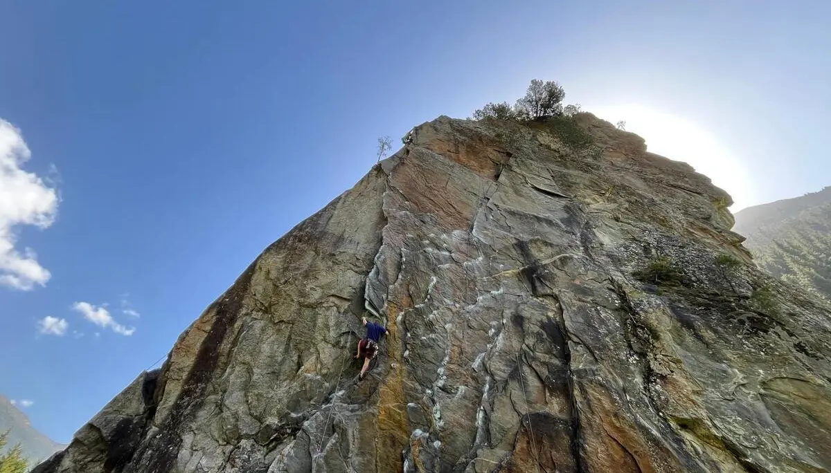 Eine Person klettert gesichert an steiler Felswand im Zillertal, Seil verläuft nach oben; helle Sonne und blauer Himmel im Hintergrund. | © DAV Markt Schwaben