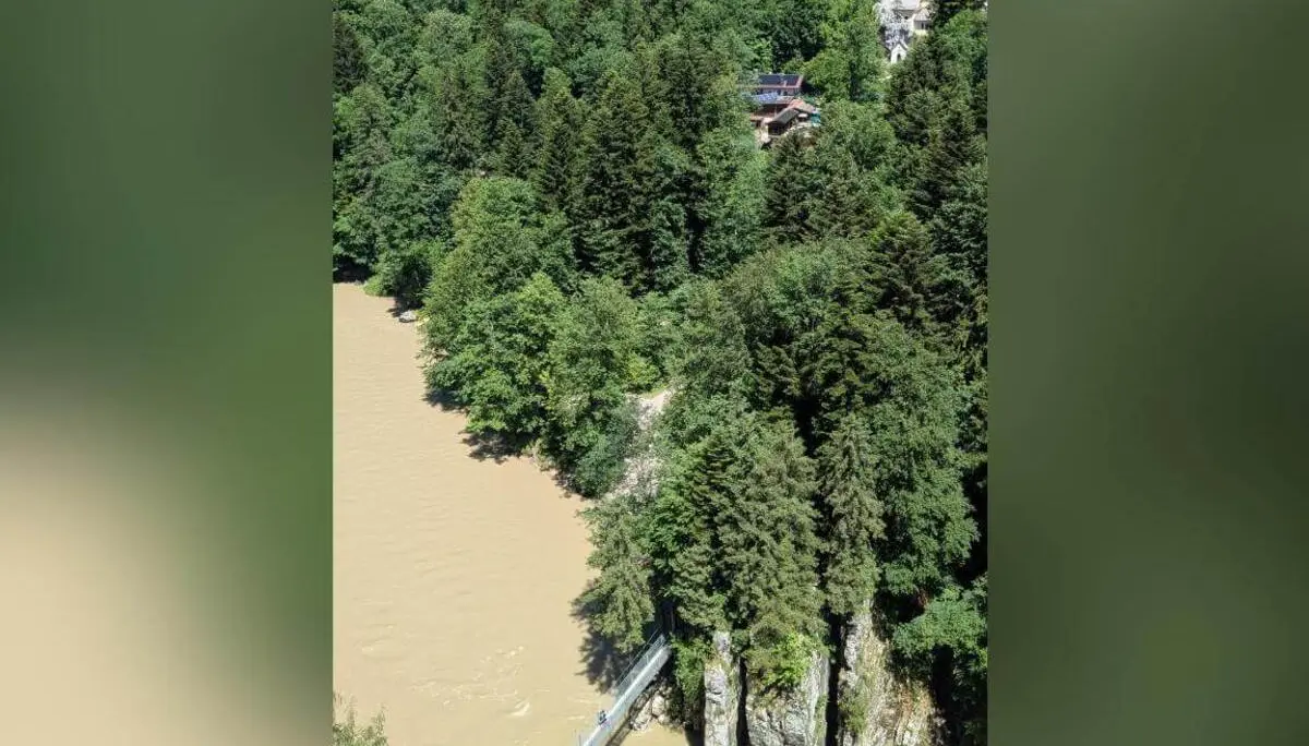 Blick von oben auf eine schmale Hängebrücke über einen braun gefärbten Fluss, umgeben von steilen Felsen und dichtem Wald. | © DAV Markt Schwaben / Silke Titze
