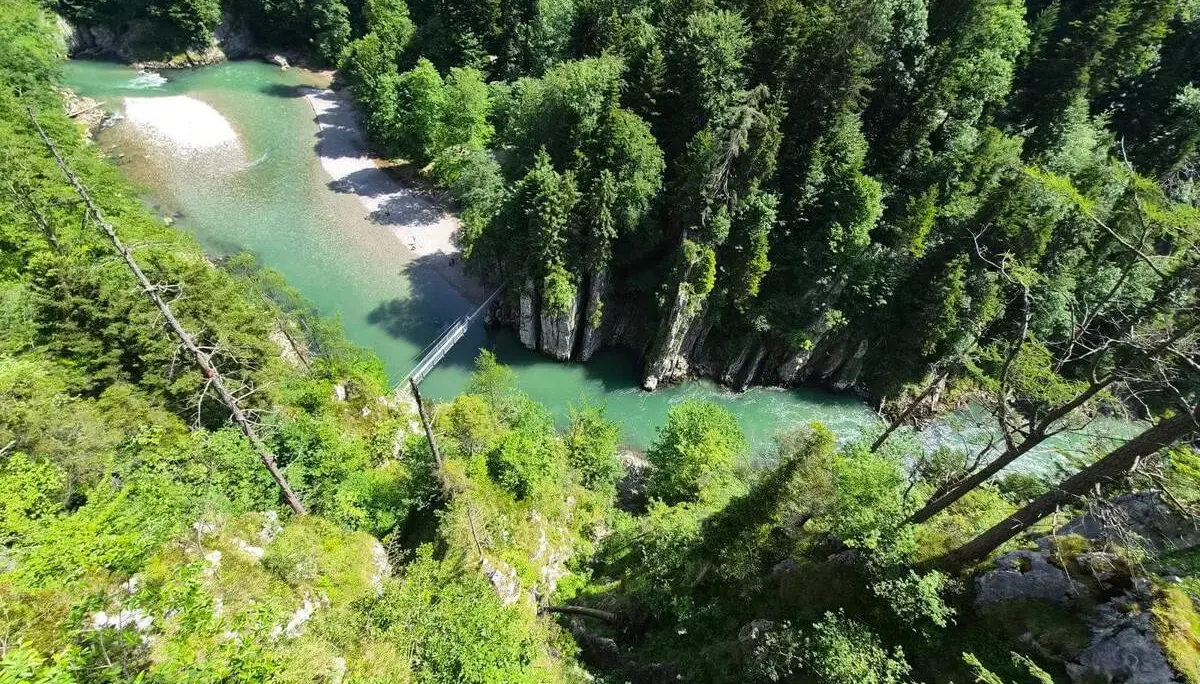 Tiefblick auf die Entenlochklamm mit türkisgrünem Fluss, steilen Felswänden, dichter Bewaldung und einer Hängebrücke. | © DAV Markt Schwaben / Hubert Inhofer